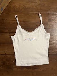 a white tank top with embroidered flowers on it