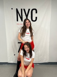 two girls posing in front of a nyc sign