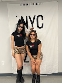 two women posing in front of a nyc zoo sign